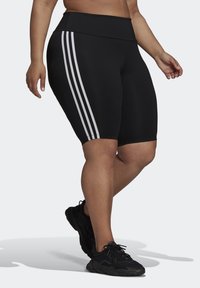 Black athletic shorts with a high waistband, featuring three white vertical stripes on each side. The material appears smooth and stretchy.