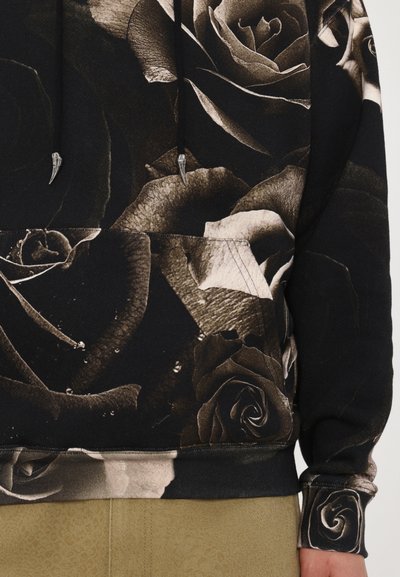 Svart sweatshirt med ett stort rosmönster i nyanser av grått, silverfärgade snoddar och en framåtfacing känguruficka.