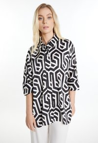 Cămășă cu un model alb-negru, cu design geometric, guler cu nasturi și mâneci până la trei sferturi. Textură de țesătură netedă.