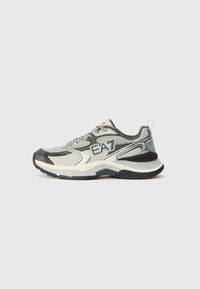 Scarpe da ginnastica grigie e bianche con materiali in rete e sintetici, caratterizzate da una suola spessa, dettagli testurizzati e un logo sul lato.