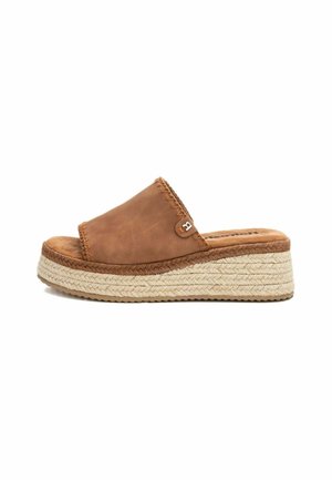 Sandalias de cuero marrón con tiras anchas y una suela de plataforma de yute trenzado. Presenta un borde cosido y un pequeño acento metálico.