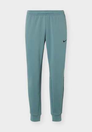 Ανοιχτό μπλε στενά φούτερ με ελαστική μέση και λογότυπο Nike στο πάνω αριστερό μηρό σε λευκό φόντο.