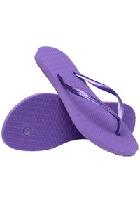 Lila gumiból készült papucsok, texturált talppal. A pántok is lilák, fényes felületűek, és cikcakk mintázatúak.