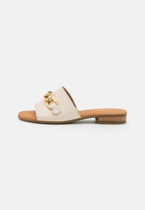 Beige sandal med åben tå, lav træsål og guldkædedetalje på bredt læderrem.