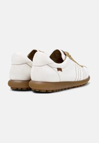 Sneakers bianche in pelle con forma arrotondata, suola in gomma color cuoio e lacci marrone chiaro. Presentano cuciture discrete e un piccolo logo sul tallone.