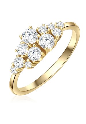 Kuldne sõrmus, millel on seitse ümmargust teemanti erinevates suurustes, kinnitatud prongide abil. Iga teemant loojub, luues kaskaadi efekti siledal bändil.