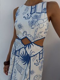 Rochie fără mâneci dintr-un material alb, cu modele botanice și de ustensile în culori albastre, având un design decupat în talie și o margine contrastantă.