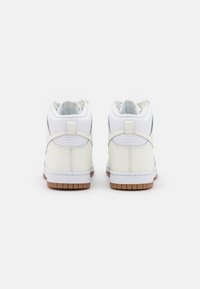 Vita höga sneakers med en slät läderöverdel, vadderad krage och en sula av gummigummi. Har en minimalistisk design och sydda detaljer.