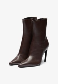 Brown leather ankle boots with a smooth finish, pointed toe, and stiletto heel. Features a sleek design and side zipper.