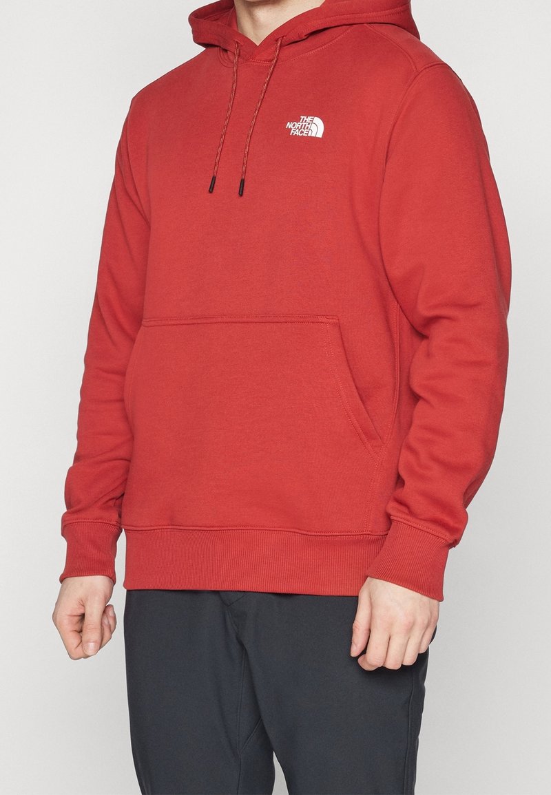 Roter Pullover mit Kapuze, langen Ärmeln und einer Kängurutasche. Verfügt über ein kleines weißes Logo auf der Brust sowie gerippte Bündchen und einen Saum.