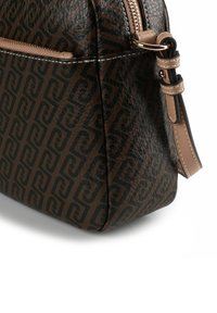 Bruine leren tas met geperst geometrisch patroon, ritssluiting en een beige riem. Gestructureerd oppervlak met contrasterende stikseldetails.