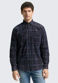 Langarmige geruite overhemd in marineblauw, rood en blauwe tinten; heeft een button-down kraag en twee borstzakken. Gemaakt van een gestructureerde stof.