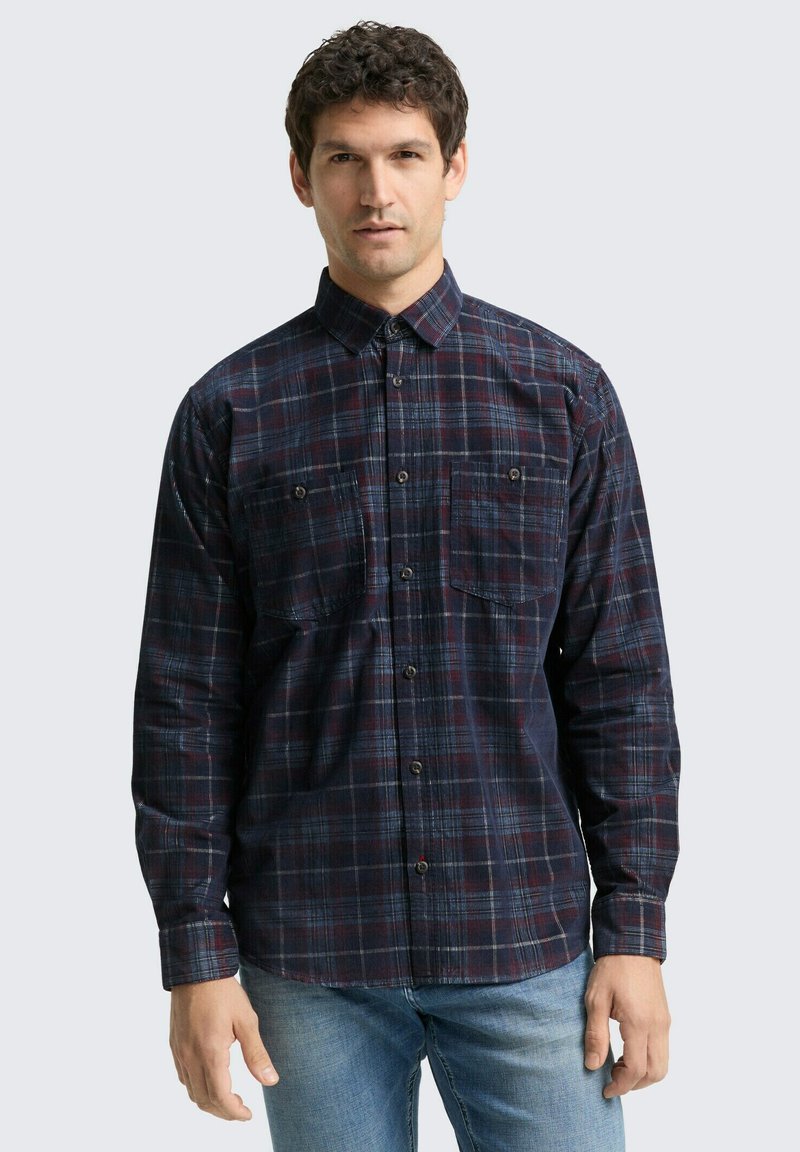 Langarmige geruite overhemd in marineblauw, rood en blauwe tinten; heeft een button-down kraag en twee borstzakken. Gemaakt van een gestructureerde stof.