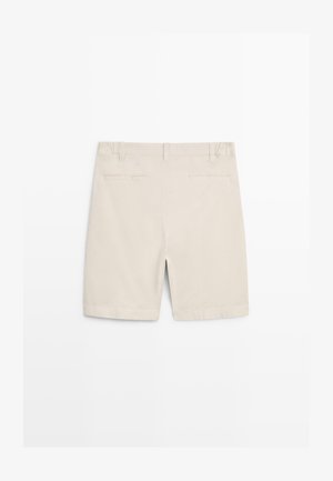 Beige knielange shorts met riemlussen, twee achterzakken met bies en een centrale achternaad op een witte achtergrond.
