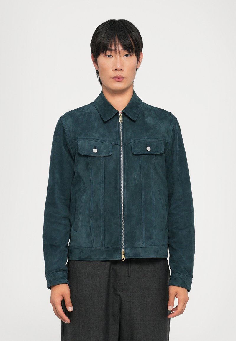 Veste en suède teal avec fermeture éclair et deux poches avant. Dispose d'un col pointu et de quincaillerie dorée. Texture lisse.