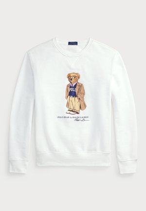 Biała bluza z grafiką niedźwiedzia w okularach, ubranym w marynarkę, koszulę i sweter z logo "POLO". Tekst poniżej brzmi "POLO BEAR by RALPH LAUREN."