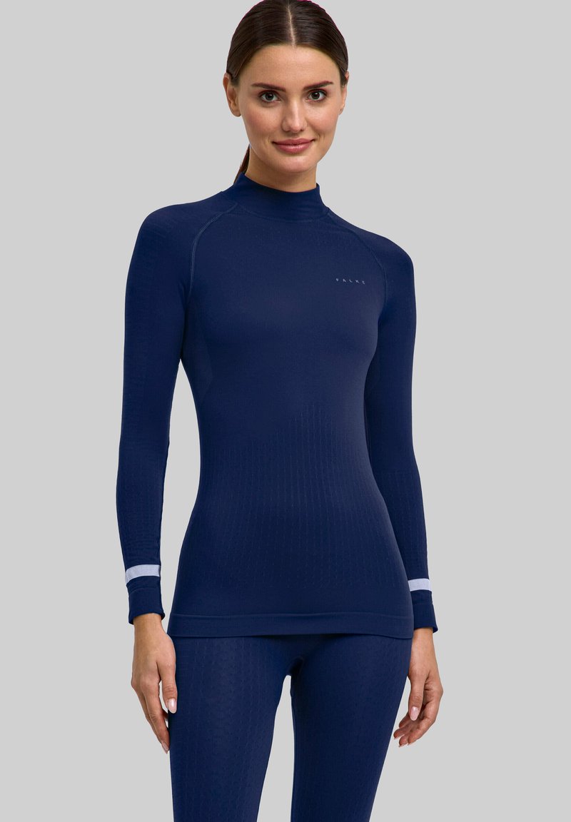Granatowy sportowy top z długim rękawem, z wysokim kołnierzem, prążkowaną fakturą i białym akcentem na mankietach. Materiał jest rozciągliwy i dopasowany.