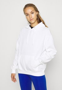 Hvit hettegenser med hette, frontlomme, snor og ribbestrikkede mansjetter, sammen med blå leggings. Glatt tekstur og avslappet passform.