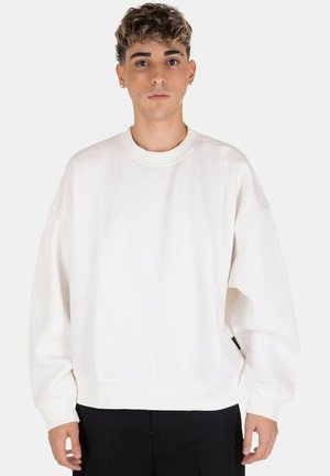 Felpa bianca oversize con collo rotondo, polsini e orlo a coste. Realizzata in tessuto morbido, presenta un'etichetta laterale discreta. Design semplice e moderno.