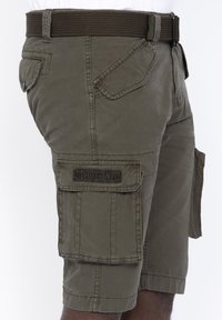Pantaloni cargo color khaki realizzati in cotone misto, con molteplici tasche, una cintura intrecciata marrone e un logo applicato sulla gamba sinistra.