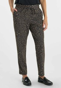 Luipaardprint broeken in bruin en zwart, met een elastische tailleband, trekkoord en zijzakken, gestyled met zwarte loafers.