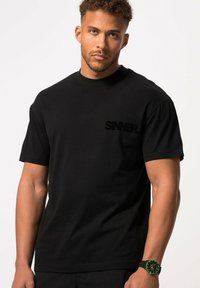 Schwarzes Baumwoll-T-Shirt mit strukturiertem "SINNER."-Logo in Schwarz, kurzen Ärmeln und einem lockeren Schnitt. Tragen mit einer schwarzen Uhr mit grünen Akzenten.