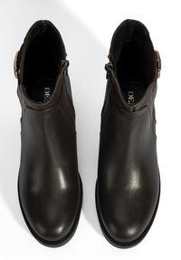 Donkerbruine leren enkelboots met een gladde afwerking, zijrits en een ronde neus; beschikt over een decoratieve accent bij de enkel.
