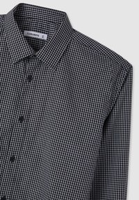 Camicia a quadri bianca e nera con colletto aperto, realizzata in tessuto tessuto. Due bottoni neri visibili sul davanti. Taglia XXL.