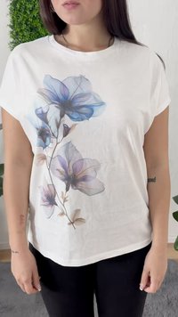 Camiseta blanca de manga corta con un diseño floral en azul y púrpura, fabricada con un tejido suave y liso, y con un corte relajado.