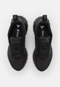 Black athletic shoes with mesh and synthetic upper, textured outsole, lace-up front, padded tongue, and contrasting logo accents.