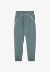 Ljust grågröna sweatpants med elastisk midja, smalnande fållar och vita sömmar längs sidorna. Mjuk, texturerad tyg.