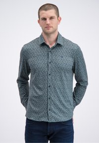 Overhemd met knopen van donkerblauwe stof met een geometrisch patroon. Heeft lange mouwen, een kraag en een klein logo op de borst.