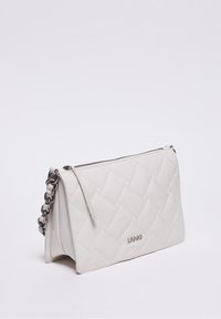 Valkoinen tikattu nahkainen olkalaukku, jossa on hopeinen ketjuhihna ja vetoketjukiinnitys, brändin logo painettuna etupuolelle.