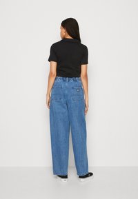 Črna kratka majica s kratkimi rokavi, modri visok pas široki kavbojke, elastičen pas, dva zadnja žepa, črne natikače.