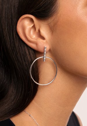 Silver hoop earrings with a textured, rectangular accent. The design features a large circular shape and polished metal finish.