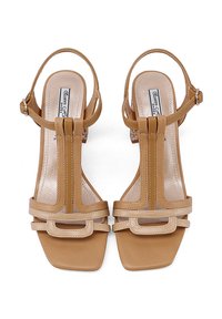 Sandali in pelle color tan con punta quadrata, dotati di doppi cinturini, chiusura a fibbia e suola piatta. Tra i dettagli di design spiccano accenti orizzontali.
