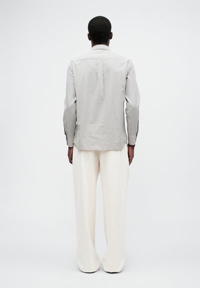 Stripete skjorte i hvit og grå, med lange ermer og en skreddersydd passform. Parret med kremfargede vide bukser.