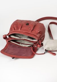 Borsa a tracolla rossa in pelle con design a pieghe, scomparti con zip e tracolla regolabile. Include una piccola pochette a righe.