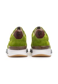 Scarpe da ginnastica in suede verde con un accento in pelle marrone sul tallone, suola intermedia bianca e suola in gomma grigia. Lacci piatti e colletto imbottito.