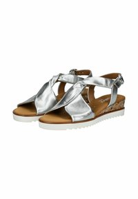 Sandalias de cuña metálicas plateadas con un acento de corcho texturizado, puntera descubierta y correas cruzadas. Presentan un cierre ajustable en el tobillo y una suela blanca.