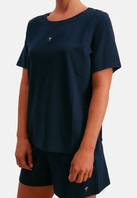 Marineblauw katoenen T-shirt met korte mouwen en een ronde hals, met een klein bloemlogo op de borst. Gecombineerd met bijpassende shorts.