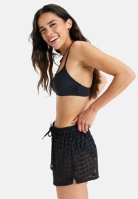 Black bikini top with thin straps and matching black crochet swim shorts featuring a grid pattern and side slits for ventilation.