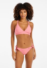Set bikini rosa con bralette triangolare testurizzato e spalline regolabili, abbinato a slip laterali con lacci e un delicato motivo geometrico.
