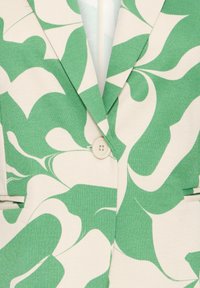 Blazer vert et blanc à motif, présentant un tissu texturé, des revers crantés, une fermeture à un bouton et des détails de poche poitrine.