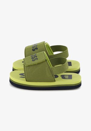 Sandali in tessuto verde con suola morbida, cinturino regolabile e audace logo "BOSS" sulla parte superiore. Presentano una soletta imbottita e una finitura testurizzata.