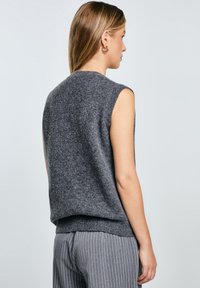 Grauer ärmelloser Strickpullover mit rundem Ausschnitt und geripptem Saum. Weiche Textur, lockere Passform und keine auffälligen Muster oder Beschläge.