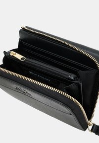 Portafoglio in pelle nera con zip dorata, numerosi scomparti per carte, comparto per monete con zip e superficie testurizzata. Presenta il logo del marchio all'interno.