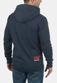 Navy blue hoodie made of soft fabric with a kangaroo pocket, features a drawstring hood and red logo text at the back with "Since 1993."