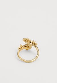 Bague en métal doré ornée d'accents floraux, avec un anneau lisse et arrondi, et des motifs de feuilles intricats. La surface texturée ajoute du détail aux pétales.