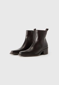 Botas de tobillo de cuero marrón con una textura suave, punta redondeada y tacón cuadrado, que cuentan con un zipper lateral y una pestaña de tela para tirar.